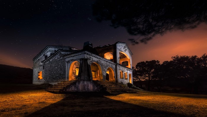 An old abandoned house at night under the stars