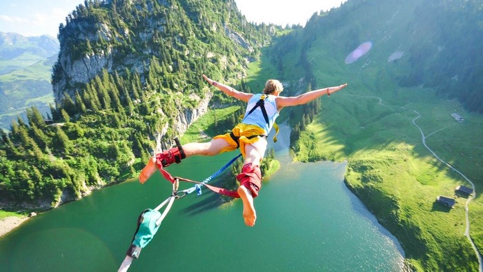 Person bungee jumping over a lake in the mountains