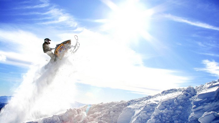 Snowmobiler jumping in the air with snow spray