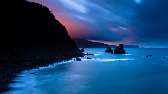 Rocky shore at twilight with ocean waves