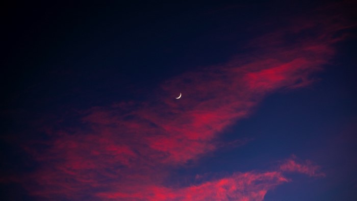 Crescent moon in a twilight sky with red clouds