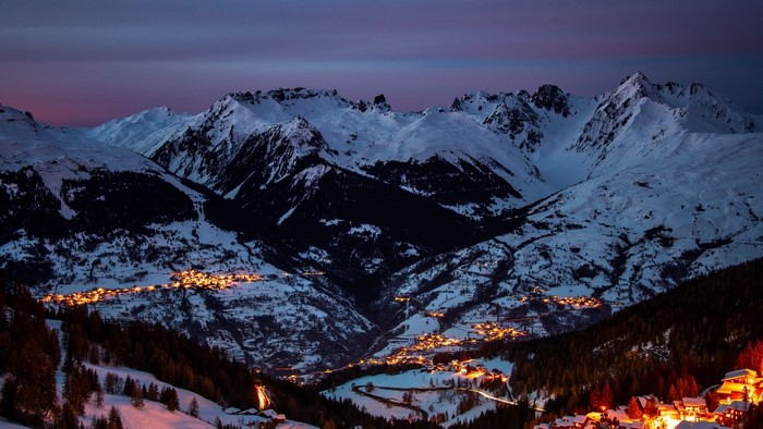 Snowy mountains with illuminated village at dusk