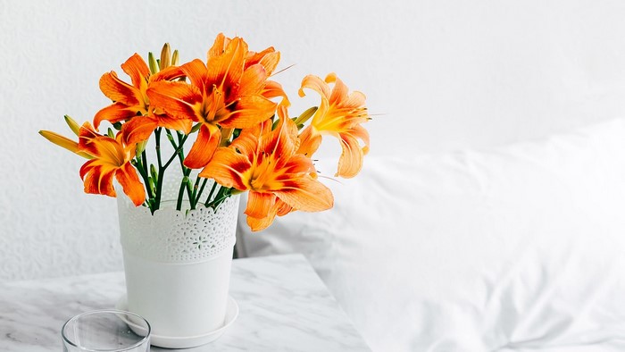 Orange lilies in a white vase on a marble table