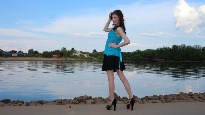Young woman in blue top and black skirt by the water