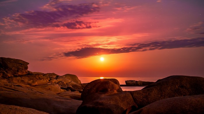 Sunset over the ocean with rocky shore