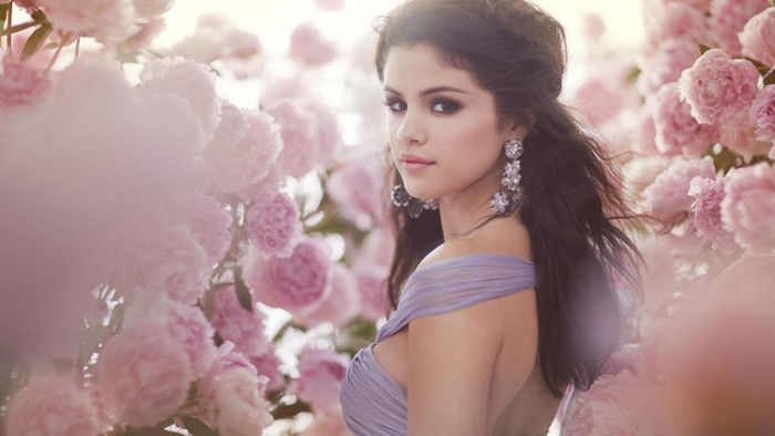 Selena Gomez in a purple dress surrounded by pink flowers