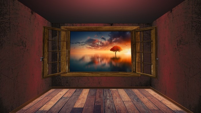 Room with a window view of a tree at sunset