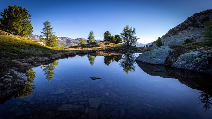 Mountain lake with reflections of trees and sky