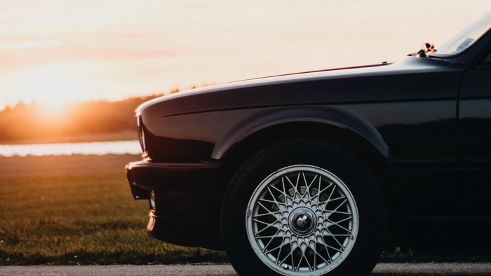 Side view of a dark car with a sunset background