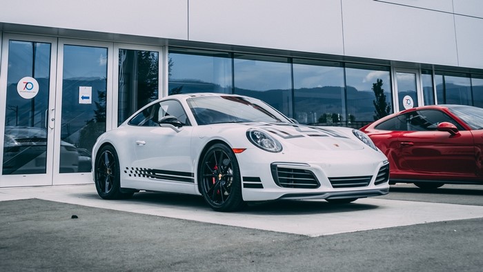 White Porsche 911 with racing stripes and red Porsche