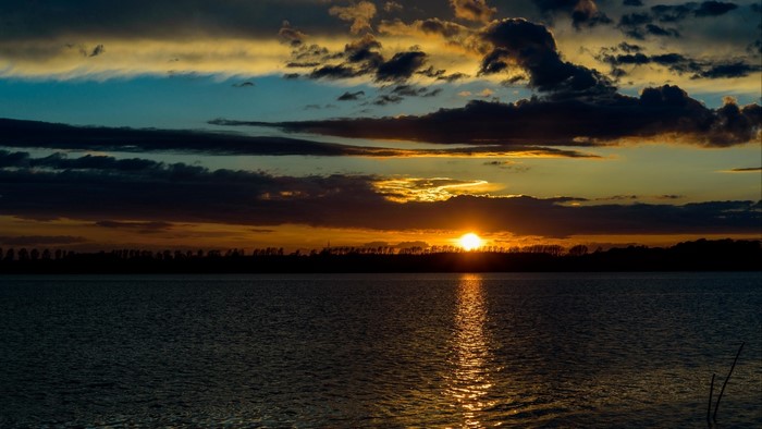 Sunset over a body of water with clouds