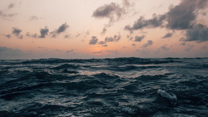 Rough ocean waves at sunset with clouds
