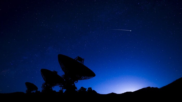 Satellite dishes under a starry night sky