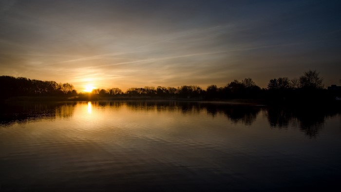 Sunset over a calm lake with trees