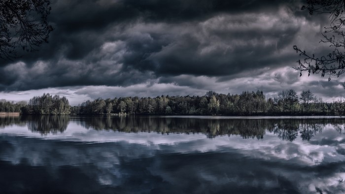 Dark Clouds Over a Reflective Lake and Forest