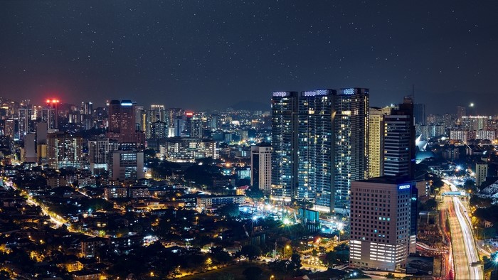 Night cityscape with illuminated skyscrapers and starry sky
