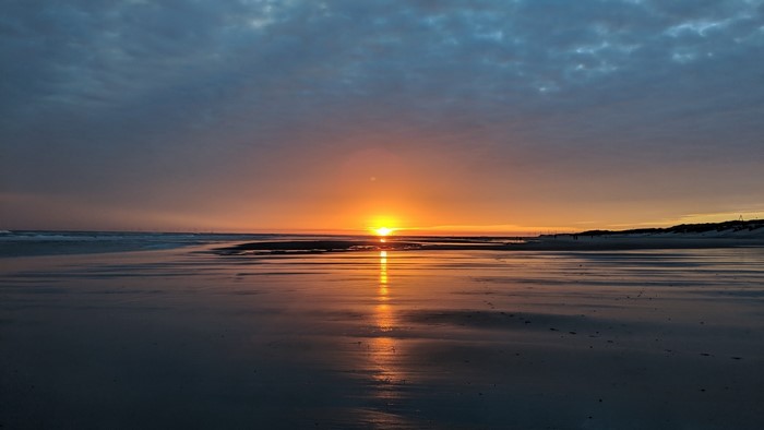 Sunset over a wet beach with clouds