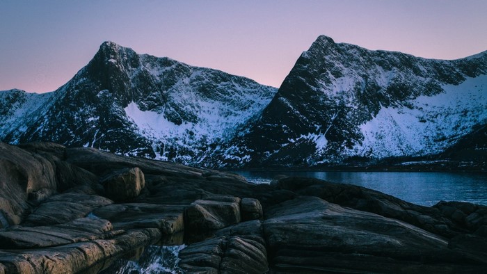 Snow-capped mountains and rocky shore in Norway
