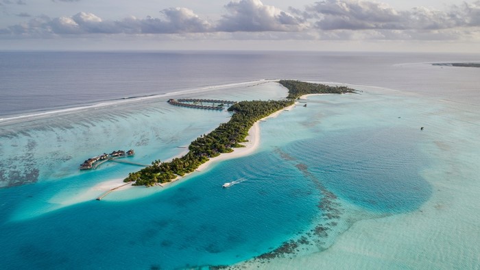 Aerial view of Maldives islands with overwater bungalows and a boat