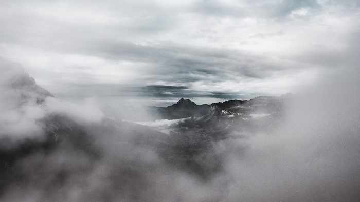 Mountain peaks shrouded in mist under a cloudy sky