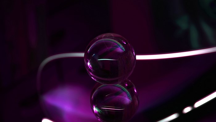 Glass ball on a reflective surface with purple lighting