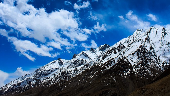 Snow-capped mountains under a blue sky with clouds