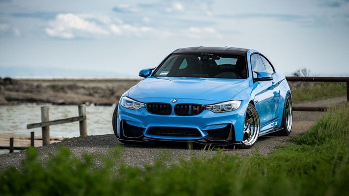 Blue BMW M4 parked by a body of water