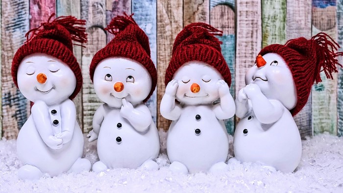 Four snowmen with red hats in the snow