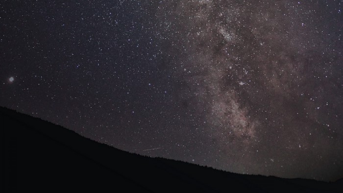 Milky Way galaxy over a dark mountain silhouette