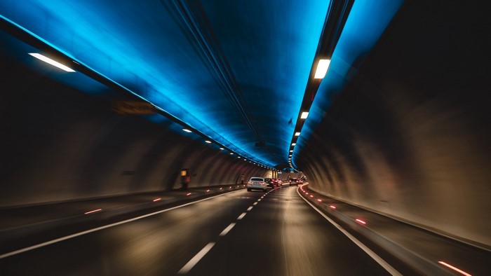 Cars driving through a tunnel with blue lights