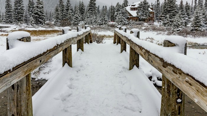 Snow-covered bridge leading to a lodge in a winter forest