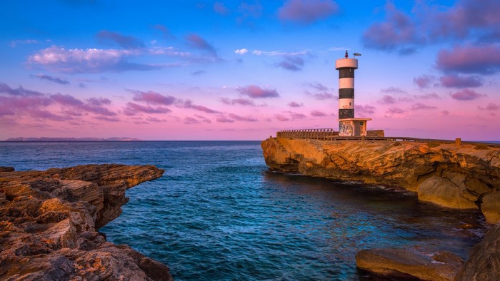 Lighthouse on a rocky coast at sunset