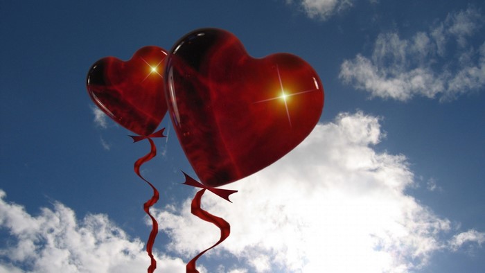 Two red heart balloons in the sky