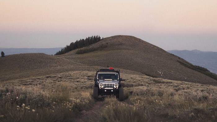 SUV on a grassy mountain trail at dusk