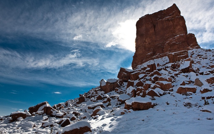Red rock formation covered in snow under a cloudy sky