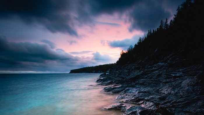 Rocky Coastline Under Dramatic Sunset Sky