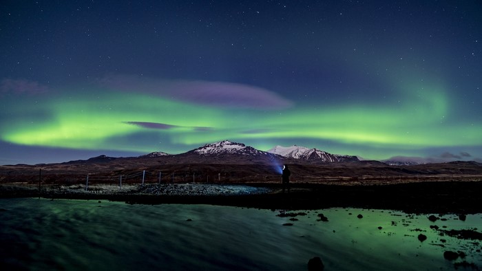 Person watching Northern Lights over mountains