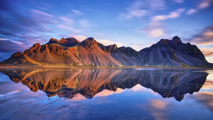 Mountains reflected in water under a cloudy sky