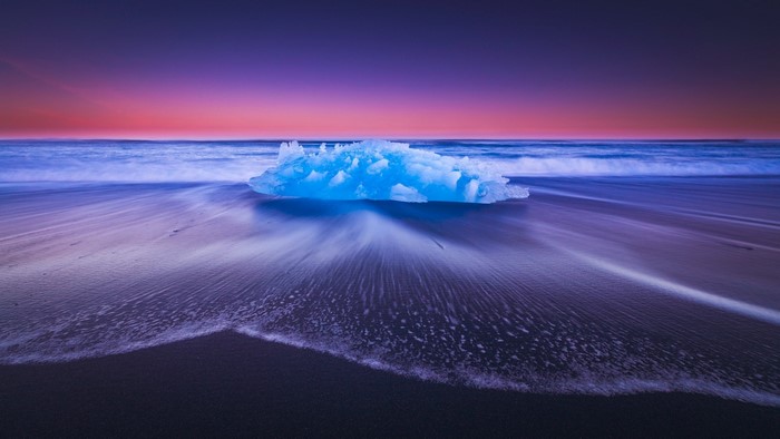 Iceberg on a beach at sunset