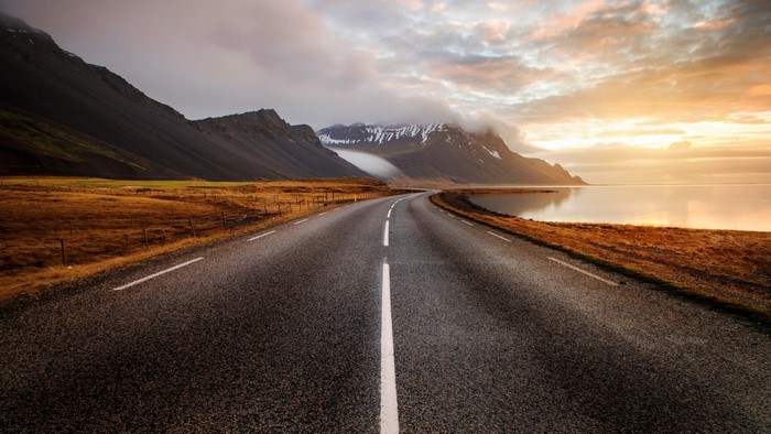 Road along the coast with mountains at sunset