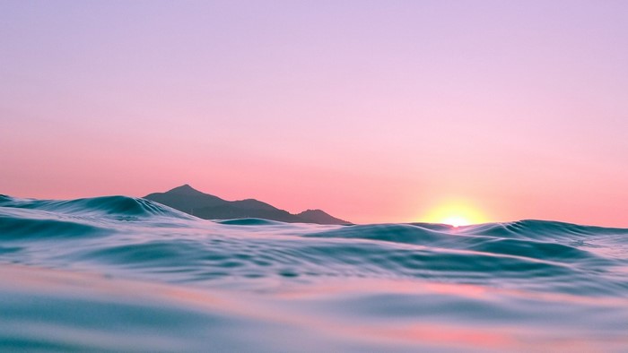 Ocean waves at sunset with mountains