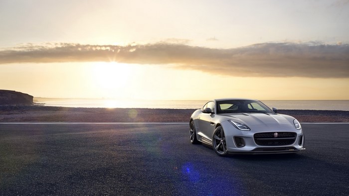 Silver Jaguar F-Type on asphalt by the sea at sunset