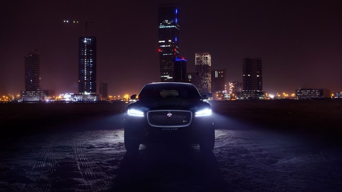 Jaguar F Pace at night with city skyline