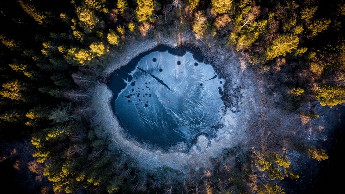 Aerial view of a frozen forest lake