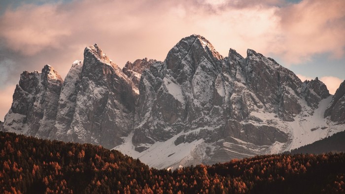 Snow-capped mountains with autumn forest