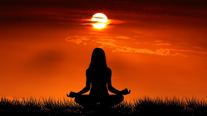Silhouette of a woman meditating at sunset
