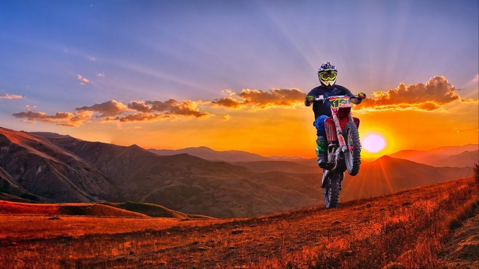 Motorcyclist performing a stunt at sunset
