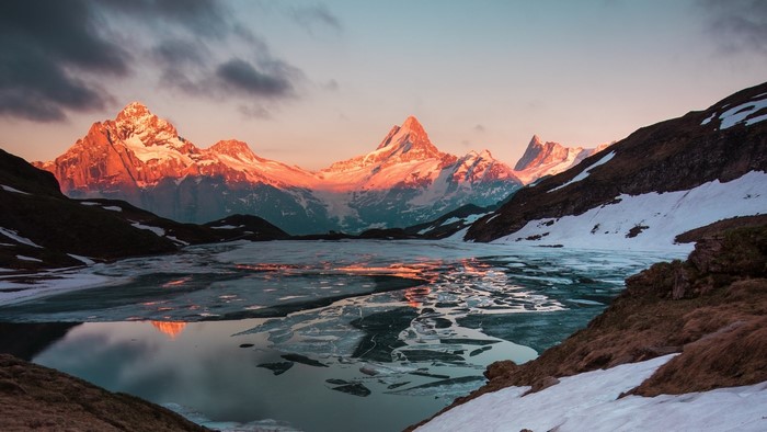 Sunrise over snow-capped mountains and a frozen lake in Switzerland