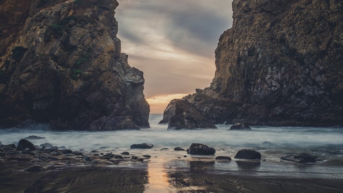 Rocky coastline with ocean waves at sunset