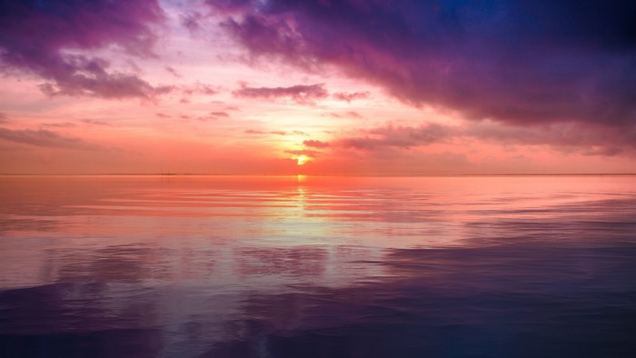 Sunset over calm ocean with colorful clouds